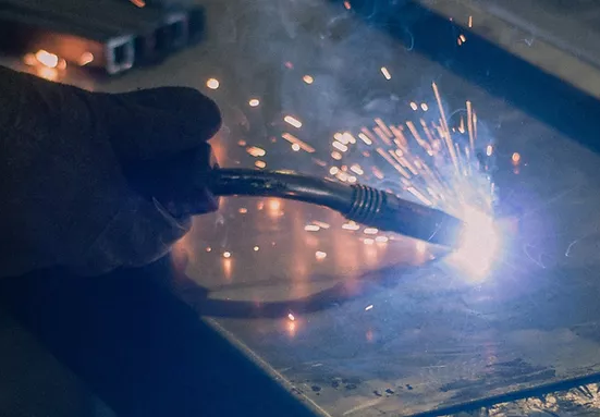Manufacturing team are cutting a metal sheet witا welding machine.