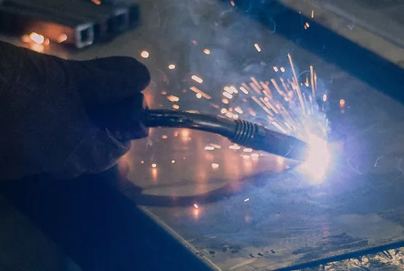 Manufacturing team are cutting a metal sheet witا welding machine.