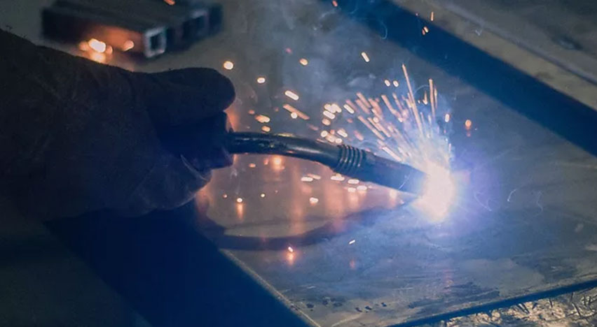 Manufacturing team are cutting a metal sheet witا welding machine.