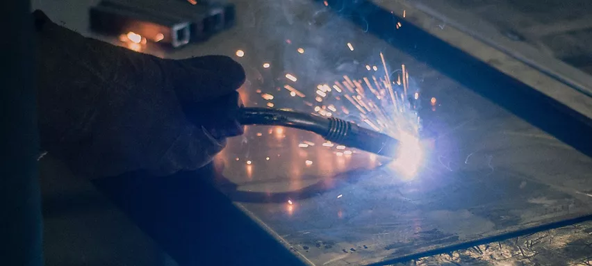 Manufacturing team are cutting a metal sheet witا welding machine.